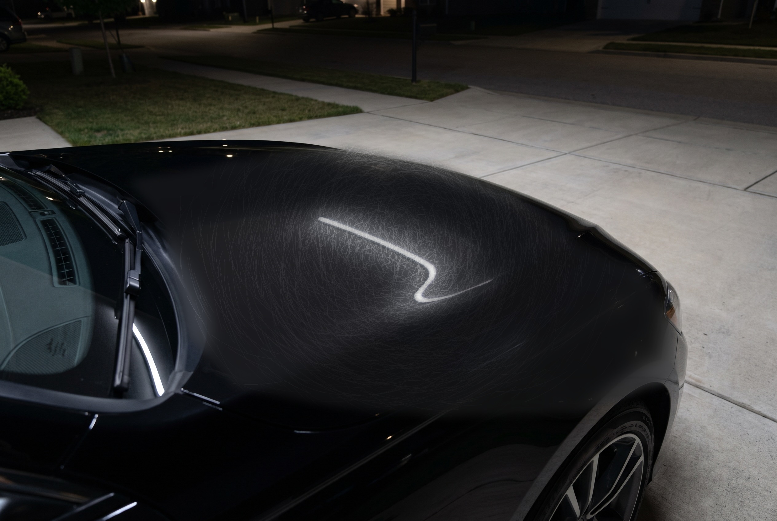 Black car hood covered in swirl marks and wash haze before paint correction